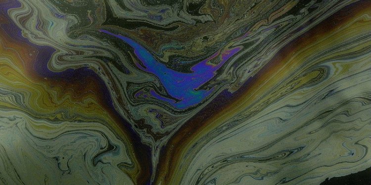 Beauty of different colours of thin cover of oil spill on water