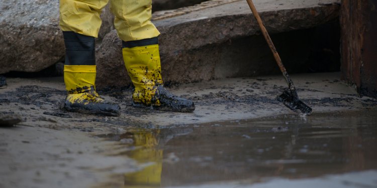 Boots of cleanup worker raking