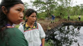 Cofan ladies remain close to the remains of acontaminated open-pit with oil at the Ecuadorean Amazonian area (picture: AP/Dolores Ochoa R.)