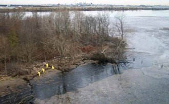 Workers clean oil from an island shoreline from the Delaware River.